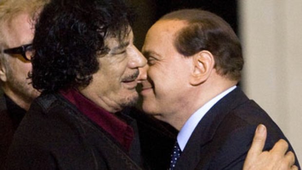 Leaders Muammar Gaddafi and Silvio Berlusconi greet each other.