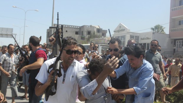 Police officers surround a man they suspect to be involved in opening fire on a beachside hotel in Sousse, Tunisia.