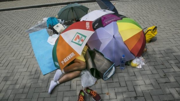 A student protester sleeps under umbrellas during a quiet moment at a protest site in Hong Kong.