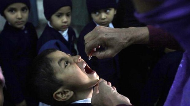 A polio worker gives vaccine drops to a child in Lahore.