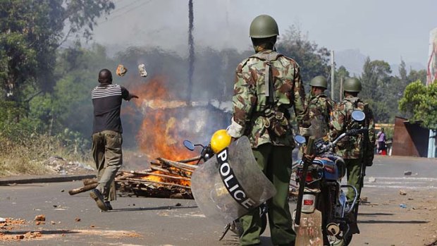 Tinderbox: Police keep watch as rioters set up road blocks in Kisumu after the presidential elections.
