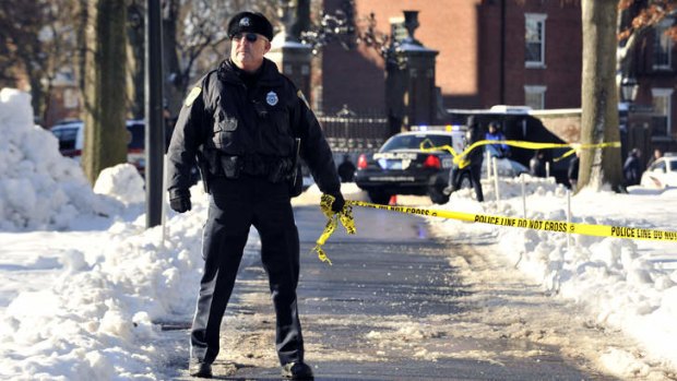 A police officer holds tape to keep people out from an area at Harvard University.