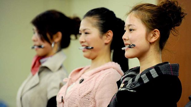 A group of young Chinese women practice standing and smiling properly during final selection to become flight attendants. Low-cost airlines are booming across the Asia-Pacific, but not in China.