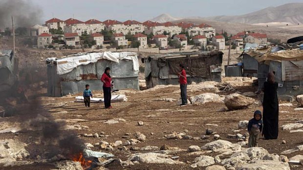 Facts on the ground: Palestinian Bedouin stand outside their shacks in the West Bank, with the growing Israeli settlement of Maaleh Adumim in the background.