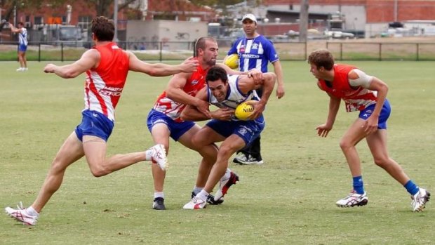 Michael Firrito is tackled by Ben Cunnington as Coach Brad Scott looks on during training.