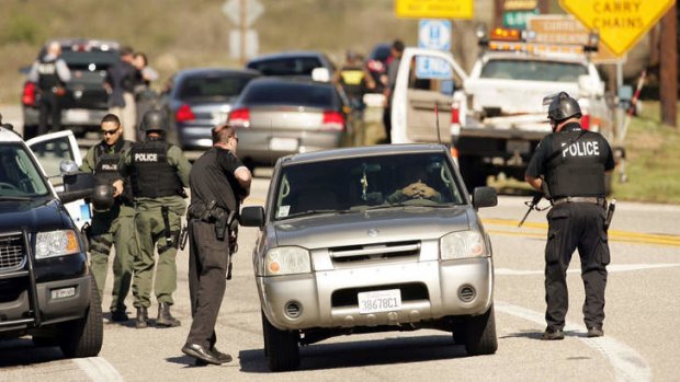 Police stand at a road block as a gunfight between police and Christopher Dorner takes place.