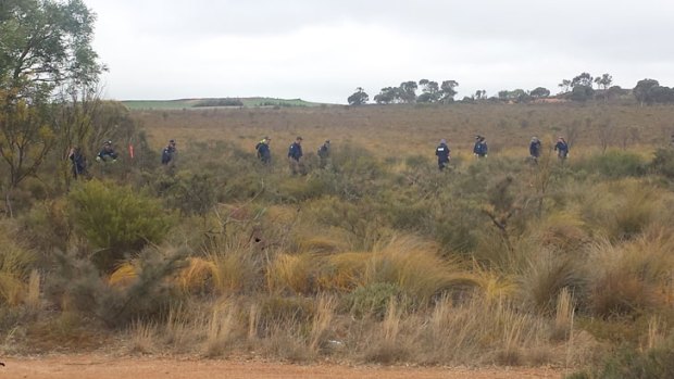 Police officers search an area of bushland in the hunt for missing teenager Hayley Dodd.