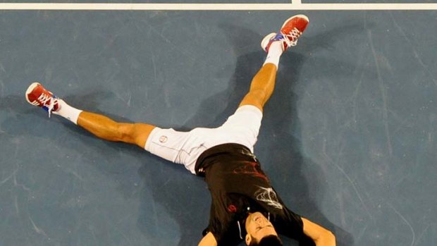 Exhausted ... Novak Djokovic collapses to the court after his epic win over Rafael Nadal.