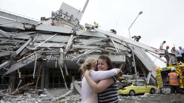 Survivors ... workmates reunite with the ruined Pyne Gould building behind them.