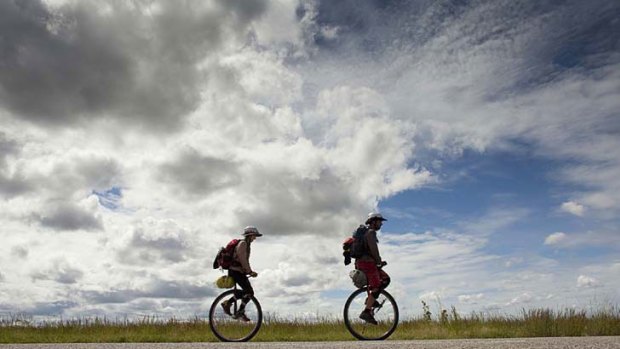 360 degree views ... unicyclists Anna Taylor and David Suede pedal down the Stuart Highway in the Northern Territory towards Adelaide. Their journey is raising money for children with cancer.