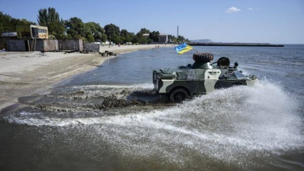 Servicemen of the Shakhtarsk battalion  drive their APC towards the water line during training session on a beach in Mariupol. US-led military exercises began in Ukraine on Monday.
