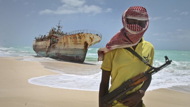 FILE - In this Sunday, Sept. 23, 2012 file photo, masked Somali pirate Hassan stands near a Taiwanese fishing vessel that washed up on shore after the pirates were paid a ransom and released the crew, in the once-bustling pirate den of Hobyo, Somalia. A U.N. official said Friday, Feb. 27, 2015 that Somali pirates have released four Thai sailors who were held hostage for nearly five years, after their ship the FV Prantalay 12 was seized by Somali pirates on April 18, 2010. (AP Photo/Farah Abdi Warsameh, File)