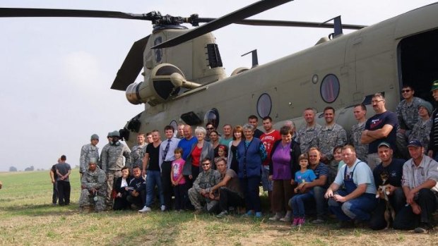 Residents of the village of Gruta, in northern Poland, pose for a photo with US troops and their Chinook helicopter in the middle of the village's field.