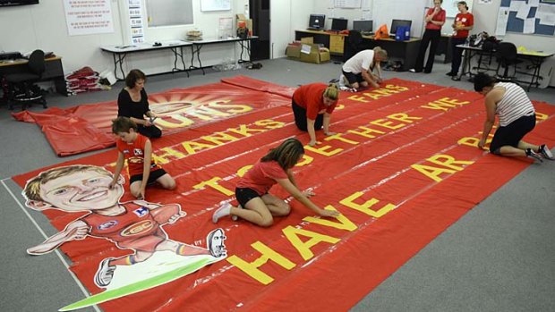 Red and ready: Members of the Sun Screamers' fan group work on the run-through banner.