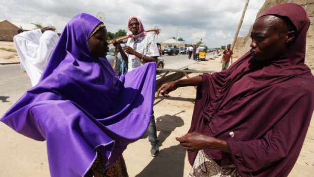 Wary: Habiba Saadu (right), a member of the vigilante force dubbed the Civilian JTF, searches a woman under her veil at a check point in Maiduguri, Nigeria.