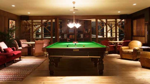 The Reading Room at The Stables features a pool table, low seating areas, chess tabletops and a large, rotating bookshelf which leads through to the Music Room.