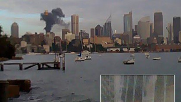 Smoke billows across the city after a blaze started when construction workers accidentally set alight a cooling tower (inset).