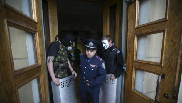 A Ukrainian policeman walks past pro-Russian activists blocking the entrance to the television station.