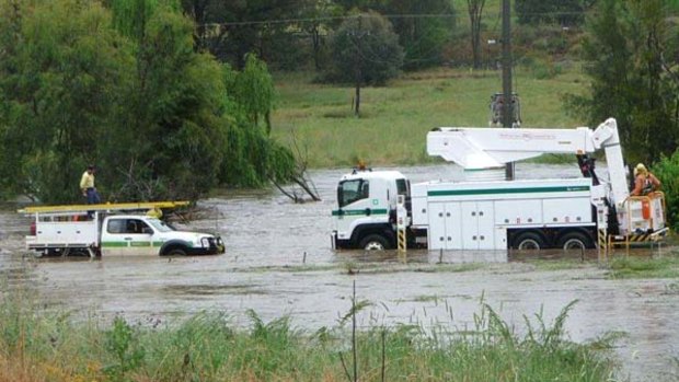 Country Energy workers brave flood waters at Mudgee to take down an overhead wire that had fallen into a swollen creek.