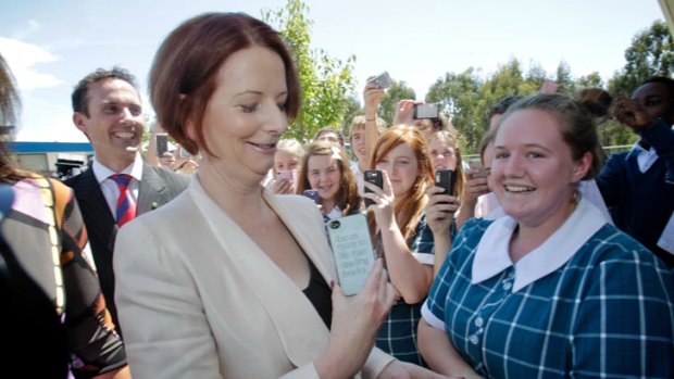 Ok to SMS the PM? Julia Gillard inspects a student's phone at St Mary Mackillop College in Canberra.