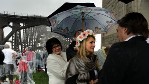 A wedding guest helps keep Mira Brodka dry as she marries John Goldbrough on the bridge yesterday morning.
