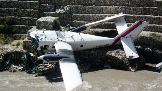 The wreckage of a Nepal Airlines Twin Otter aircraft lies near the river after crashing in Jomsom.