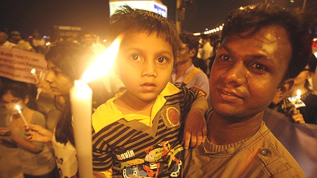 A boy holds a candle as his father carries him during a peace rally beside the landmark Marine Drive, in memory of those killed in the terror attacks in Mumbai November 30, 2008. Indian Prime Minister Manmohan Singh on Sunday said he would increase the size and strength of the country's anti-terrorist forces after militant attacks in Mumbai killed nearly 200 people.      REUTERS/Jayanta Shaw (INDIA)