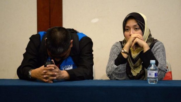 Strain on both sides ... Two members of the Malaysia Airlines special assistance team react as relatives of passengers on the missing Malaysia Airlines Flight MH370 are told those on board the jet would be brought to a "recovery area" on Thursday.