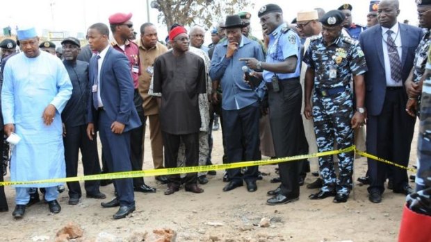 Nigerian President Goodluck Jonathan (centre, blue shirt) and Nigerian Senate President David Mark (centre, red hat) inspect the Abuja bus depot that was blown up by the Boko Haram on Monday. 
