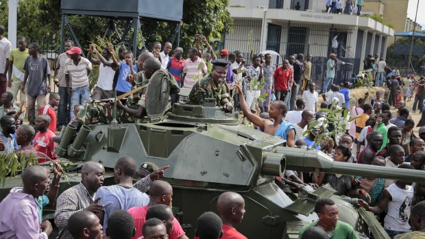 Demonstrators celebrate what they perceive to be an attempted military coup d'etat, with army soldiers riding in an armored vehicle in the capital Bujumbura, Burundi.