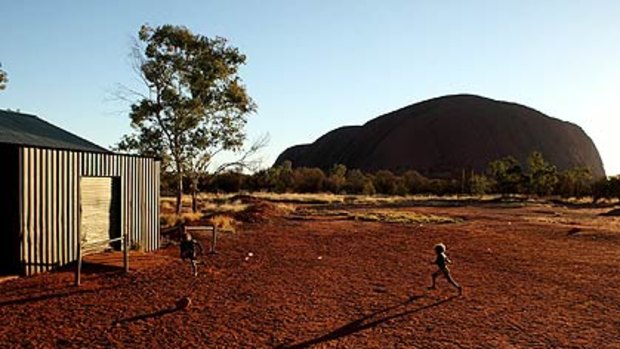 Long shadows of intervention   ...  youngsters at play in the shadow of Uluru near the settlement of Mutitjulu.