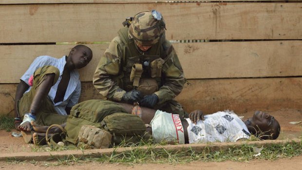 A French army medic gives first aid emergency medical care to two injured looters who were shot at as they were being chased away by people who they were looting from, on January 11, 2014, near the 'Reconciliation crossroad' in Bangui.