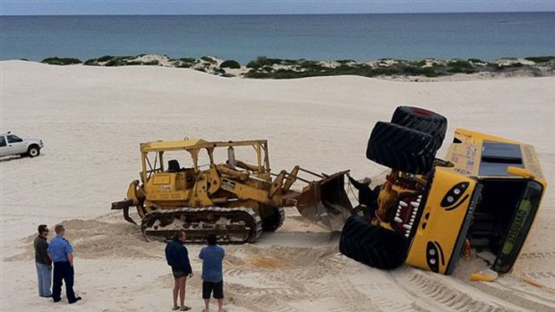 A bulldozer is called in to retrieve the four-wheel-drive after it rolled over in a dune crash.