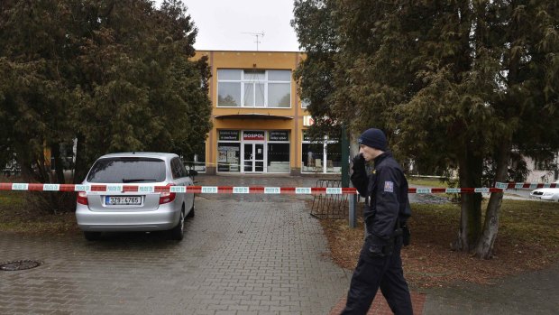 A police officer patrols near a restaurant where a gunman opened fire in Czech town Uhersky Brod. The 60-year-old man shot eight people dead before taking his own life. 