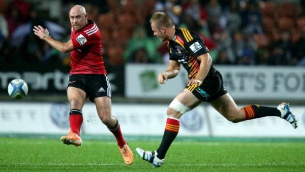 Willi Heinz gets a kick away under pressure for the Crusaders fro Chiefs opponent Sam Cane.