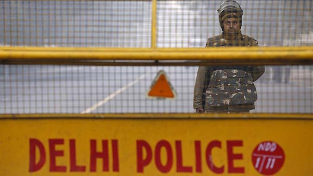 An Indian policeman stands guard at a barricade to stop protesters on Saturday after a woman gang raped died in a Singapore hospital.