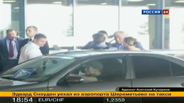 Fugitive former U.S. spy agency contractor Edward Snowden (centre) talks with Russian lawyer Anatoly Kucherena (second right) in front of a car at Moscow's Sheremetyevo airport.