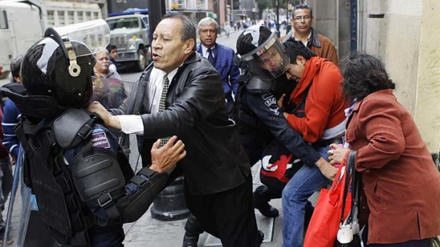 Confrontation: People clash with riot policemen who tried to arrest a protester in Mexico City.