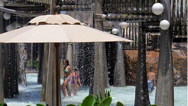 Water cascades onto visitors at the Menehune Bridge, a spray park at Disney's Aulani resort on Oahu, Hawaii.