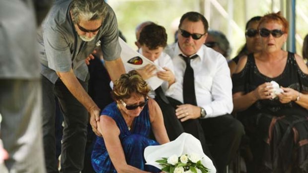 Danny McGuire holds son Zachary as a mourner places flowers on the coffin of his wife Llync.