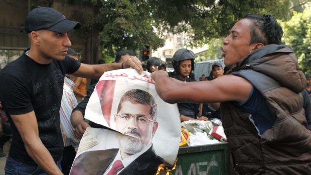 Local residents burn a poster of ousted President Mohamed Mursi, which was taken after Mursi supporters fled, during clashes in central Cairo.