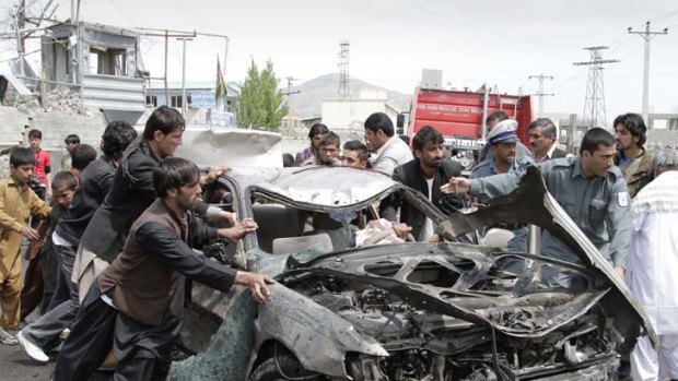 Close encounters ... Afghans push a damaged car away from the scene of a militant suicide car bomb attack which occured just hours after US President Barack Obama's surprise visit.