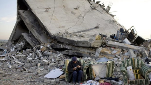 A Palestinian man sits near the ruins of a building destroyed by Israeli airstrikes in the northern area of Jabaliya, near Gaza City,
