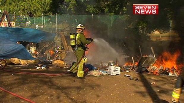 A firefighter hoses down flames at the Musgrave Park Aboriginal Tent Embassy.