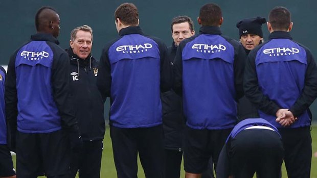 Mario Balotelli (left) listens to manager Roberto Mancini (second right) during a training session at the Carrington facility in Manchester on Friday.