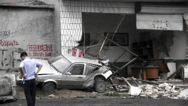 A policeman walks near a smashed car and shop at Yuanshi county, in north China s Hebei province. A drunken shovel loader driver went on a rampage in northern China, smashing into shops and vehicles and killing 11 people. Photo: AP