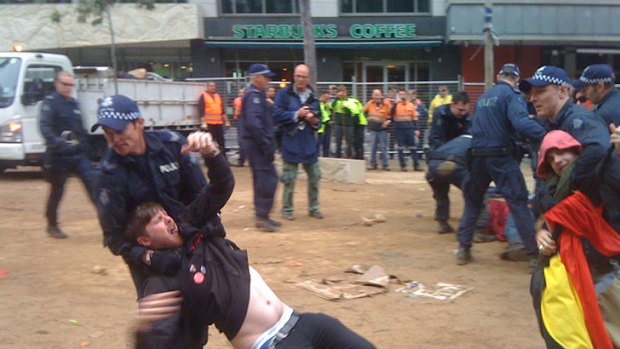 A protester is dragged out of City Square by a police officer during Friday's violent clashes.