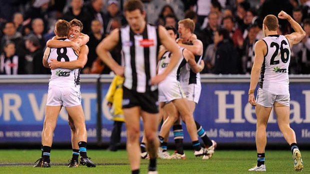 Collingwood is left dejected as Port Adelaide players celebrate their upset win at the MCG on Saturday night. Earlier in the day, the Dockers were surprise winners over the Cats.