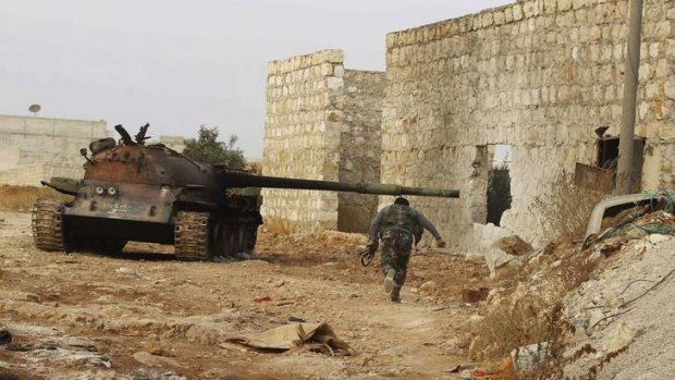 Battleground: A fighter runs beside a tank in the Base 80 area of Aleppo.