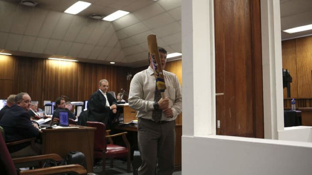 Demonstration:  A policeman takes part in the reconstruction of hitting of the door with the cricket bat during Pistorius's trial.